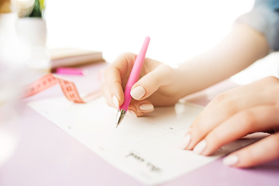 female-hands-holding-pen-trendy-pink-desk (1).jpeg