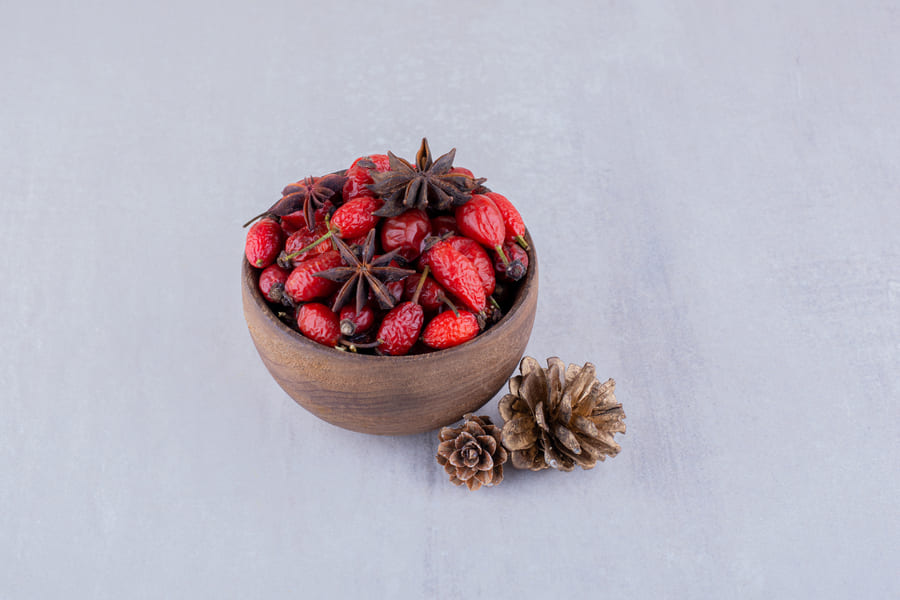 two-pine-cones-wooden-bowl-hips-anise-white-background (1).jpeg
