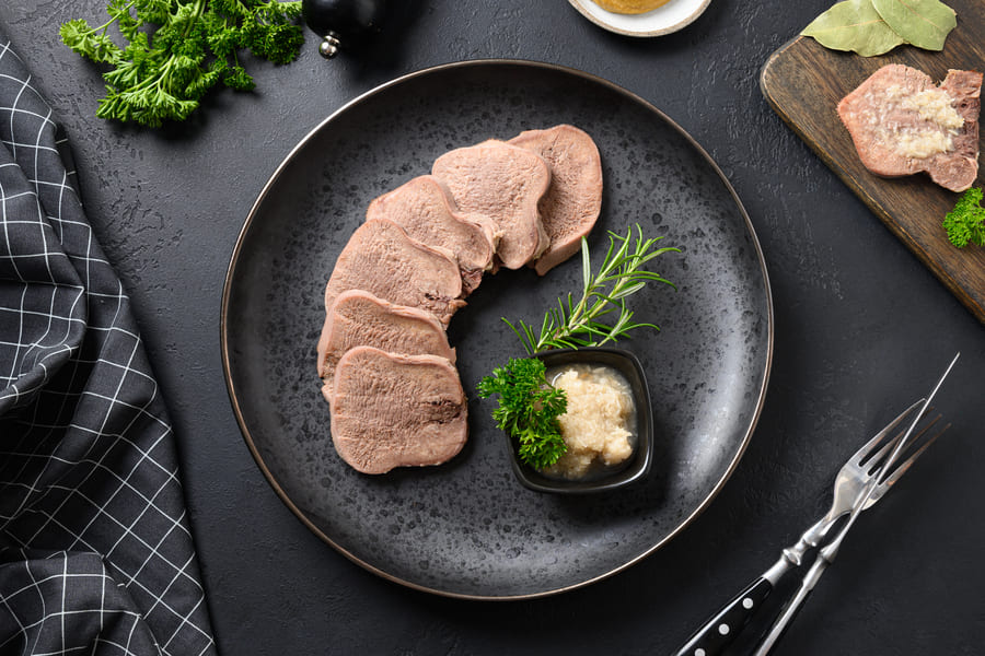 beef-tongue-served-horseradish-sauce-rosemary-sprig-black-table (1).jpeg
