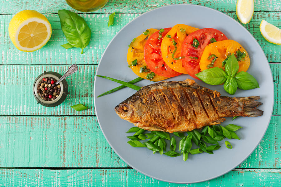 fried-fish-carp-fresh-vegetable-salad-wooden-table-flat-lay-top-view (1).jpeg