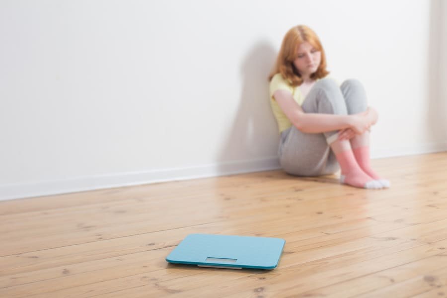 sad-teenager-girl-with-scale-wooden-floor (1).jpeg